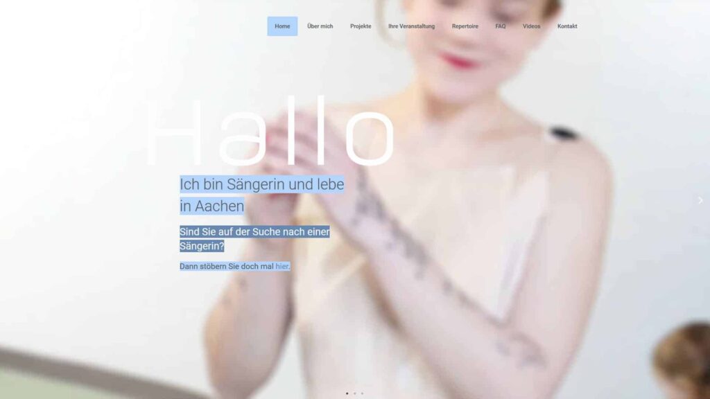 Ein verschwommenes Bild einer tätowierten Frau in einem ärmellosen Top. Ein überlagerter weißer und blauer Text in deutscher Sprache stellt sie als in Aachen lebende Sängerin vor, lädt die Nutzer ein, ihre Dienstleistungen zu erkunden, und weist auf ihre Kompetenz im Bereich Webdesign Aachen hin.