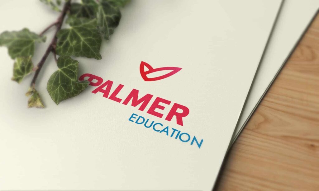 Eine Nahaufnahme eines Ordners mit dem "Palmer Education"-Logo in Rot und Blau, teilweise verdeckt von grünen Efeublättern auf einer hellen Holzoberfläche - eine ideale Inspiration für jeden Webdesigner in Aachen, der auf der Suche nach frischen Ideen ist.