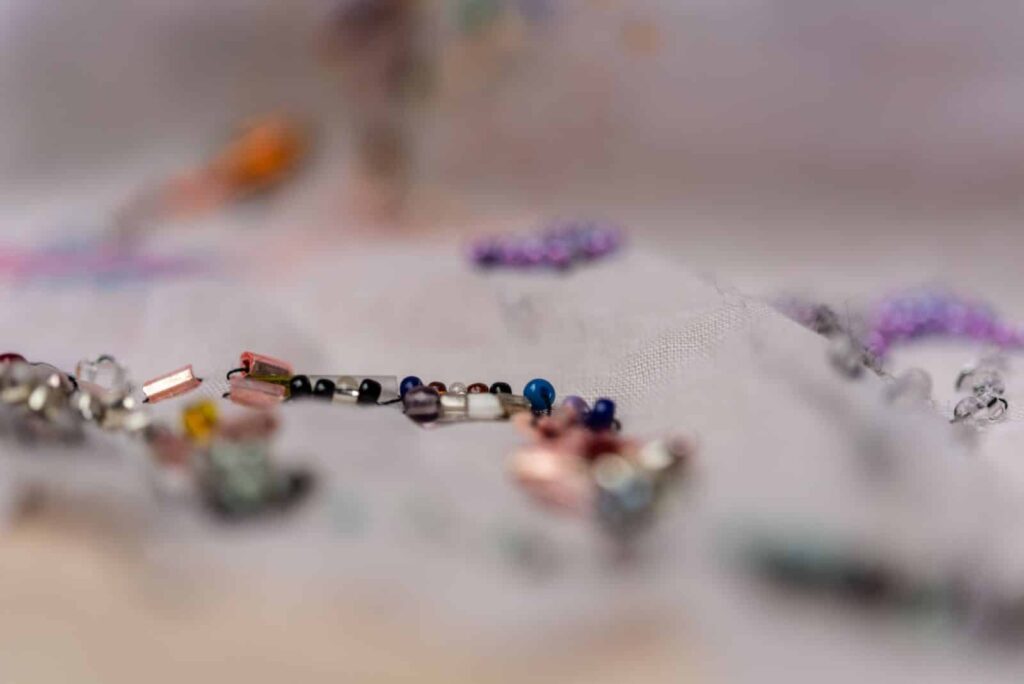 Eine Nahaufnahme von verstreuten kleinen, bunten Perlen auf einer weißen Fläche, wobei der größte Teil des Bildes unscharf ist und nur ein paar Perlen in der Mitte scharf abgebildet sind - perfekt für ein kreatives Portfolio eines Webdesigners in Aachen.