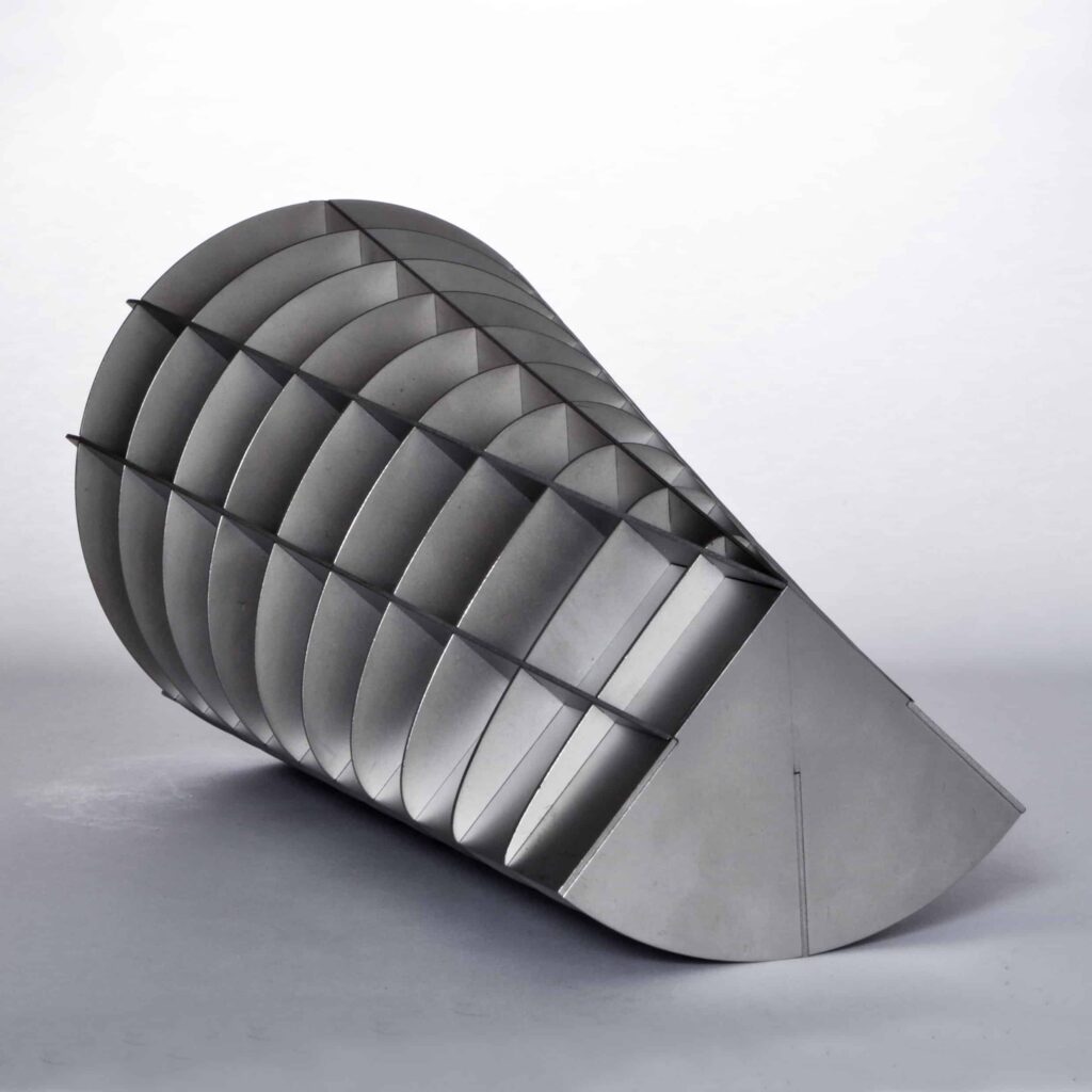 Eine minimalistische, metallische, geometrische Skulptur, die aus gebogenen, sich kreuzenden Paneelen besteht, die eine halbzylindrische, muschelartige Struktur bilden, die vor einem schlichten weißen Hintergrund steht und den eleganten Stil widerspiegelt, den die besten Webdesign-Experten in Aachen bevorzugen.