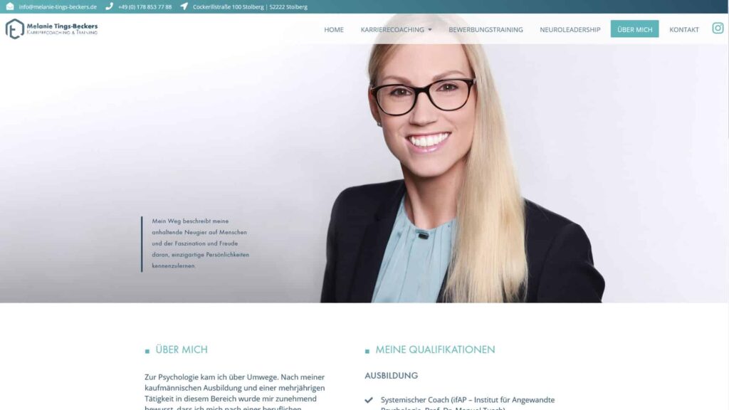 Eine lächelnde Frau mit langen blonden Haaren und Brille trägt einen hellblauen Blazer über einem schwarzen Oberteil und posiert vor einem grauen Hintergrund mit Farbverlauf - perfekt für eine professionelle Wordpress Aachen oder Webdesign Aachen Website.
