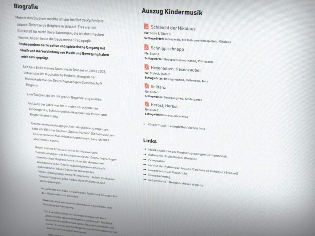 Eine deutschsprachige Website, die von einem Aachener Webdesigner erstellt wurde, bietet eine Biografie auf der linken Seite, Kindermusik in der Mitte und Links auf der rechten Seite - alles in einem klaren, minimalistischen Layout mit schwarzem und rotem Text.