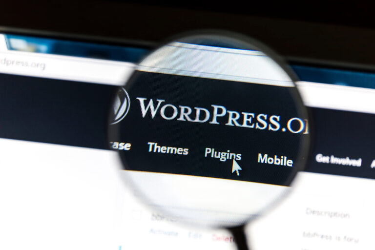 Eine Nahaufnahme eines Computerbildschirms mit der WordPress.org-Website. Eine Lupe markiert den Menüpunkt „Plugins“. Ein Mauszeiger zeigt auf die Option „Plugins“.